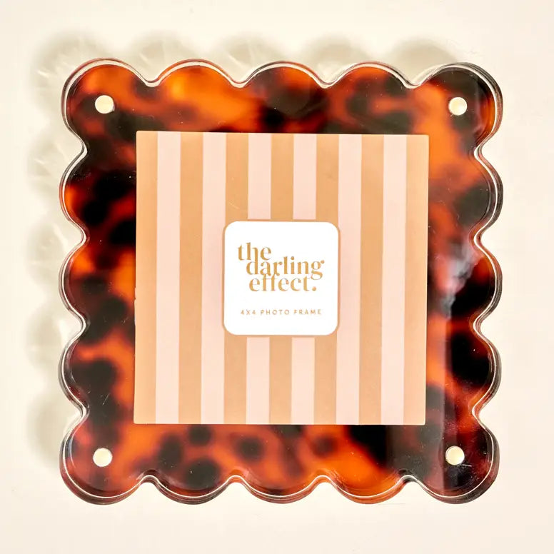 Tortoiseshell patterned acrylic frame with striped design and 'the darling effect' branding inside the frame on a beige background