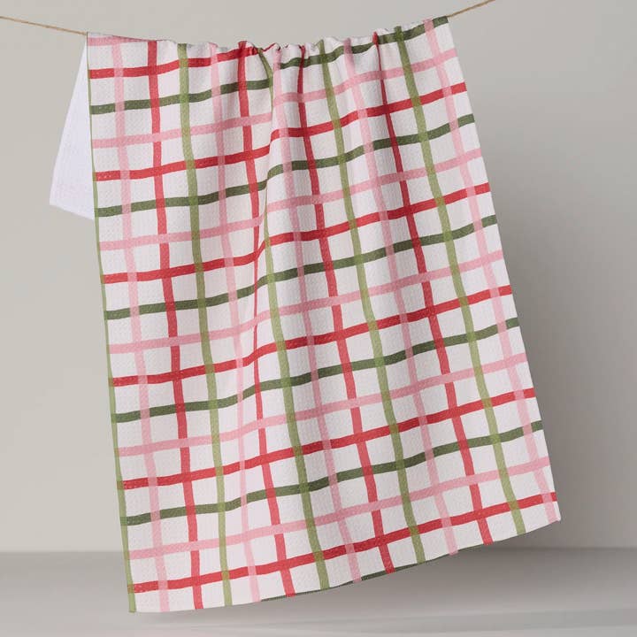 festive plaid tea towel hanging on a clothesline on a grey background