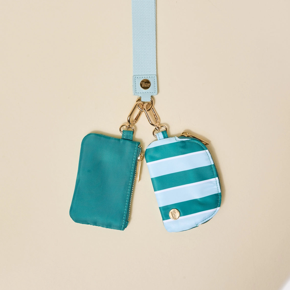 Two small pouches with a strap on a beige background