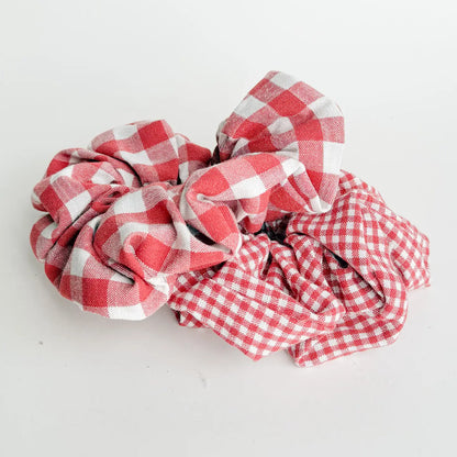 2 red gingham scrunchies, one with large the other small check patterns arranged on a white background