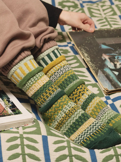 person wearing Fiddlehead Crew Socks sitting on a bed reading a magazine