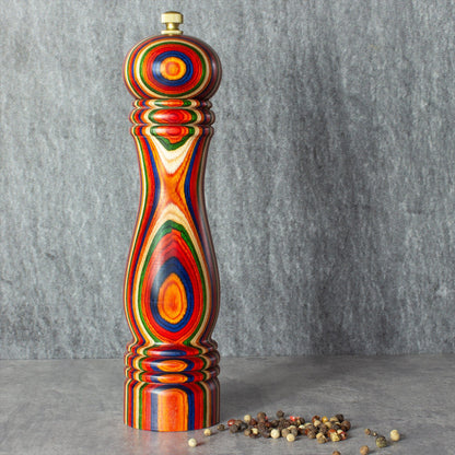 marrakesh pepper grinder on a grey countertop with peppercorns next to it.