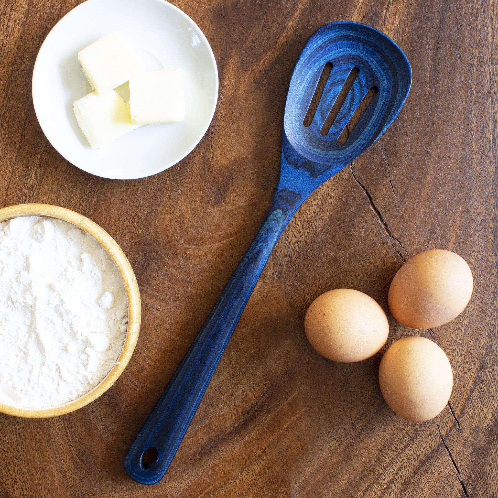 malta slotted spoon arranged on a wooden table with sugar, butter, and egss.