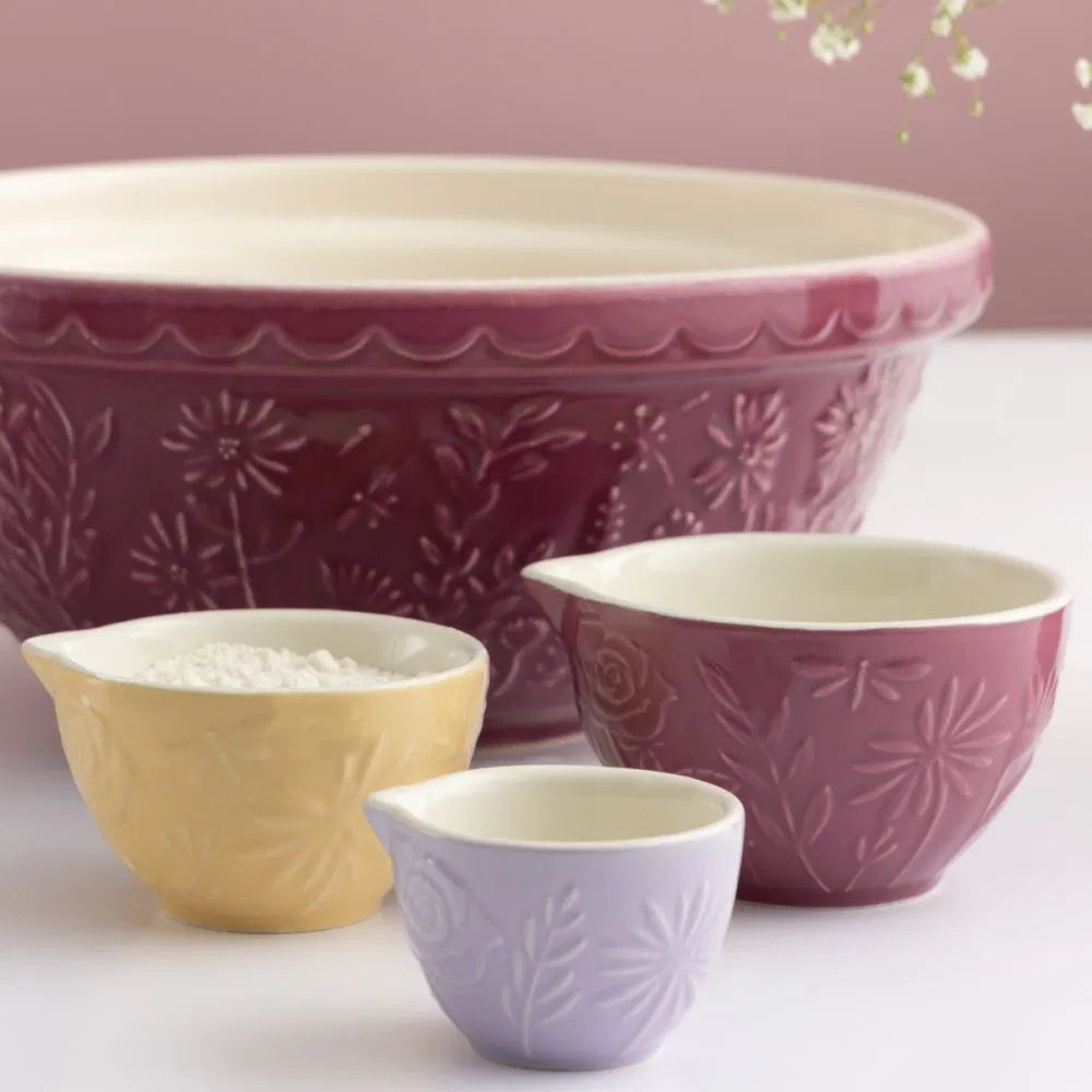 3 sizes and colors of measuring cups set on a counter with a mixing bowl.