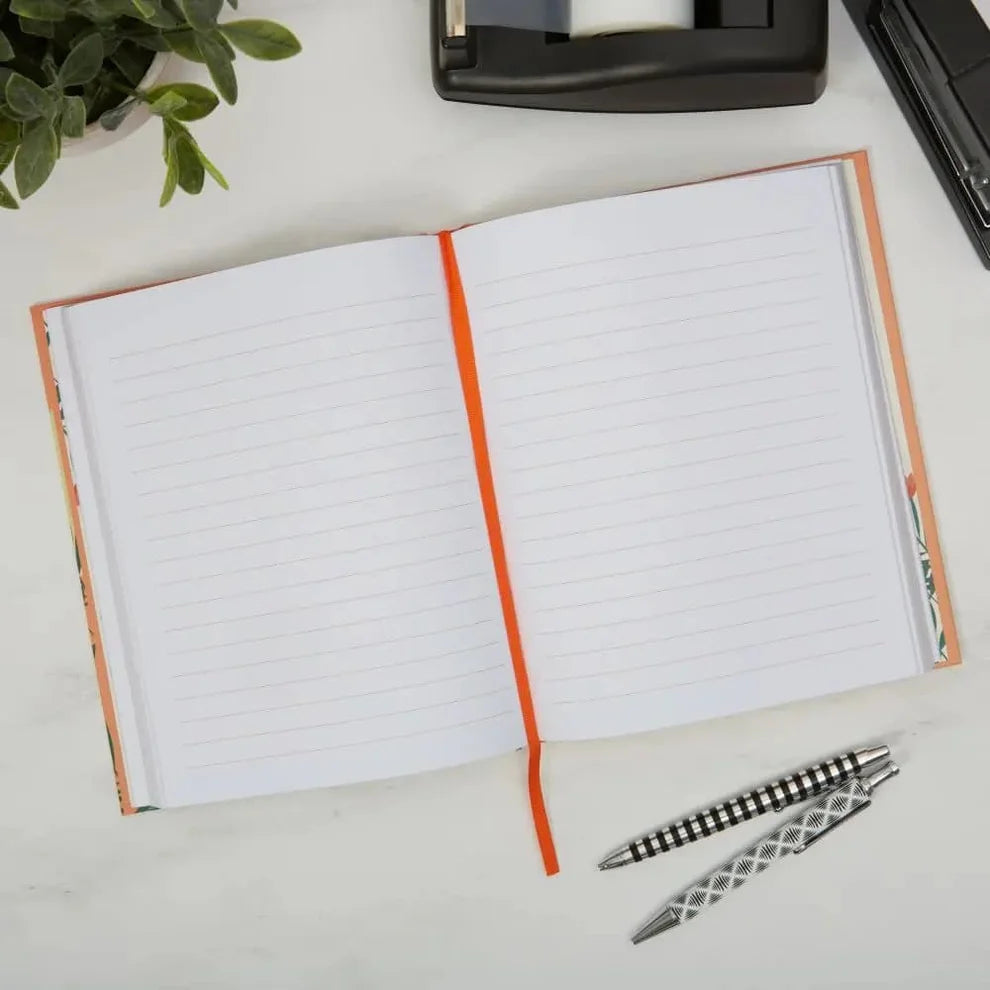 Open notebook with lined pages on a desk with a pen and plant