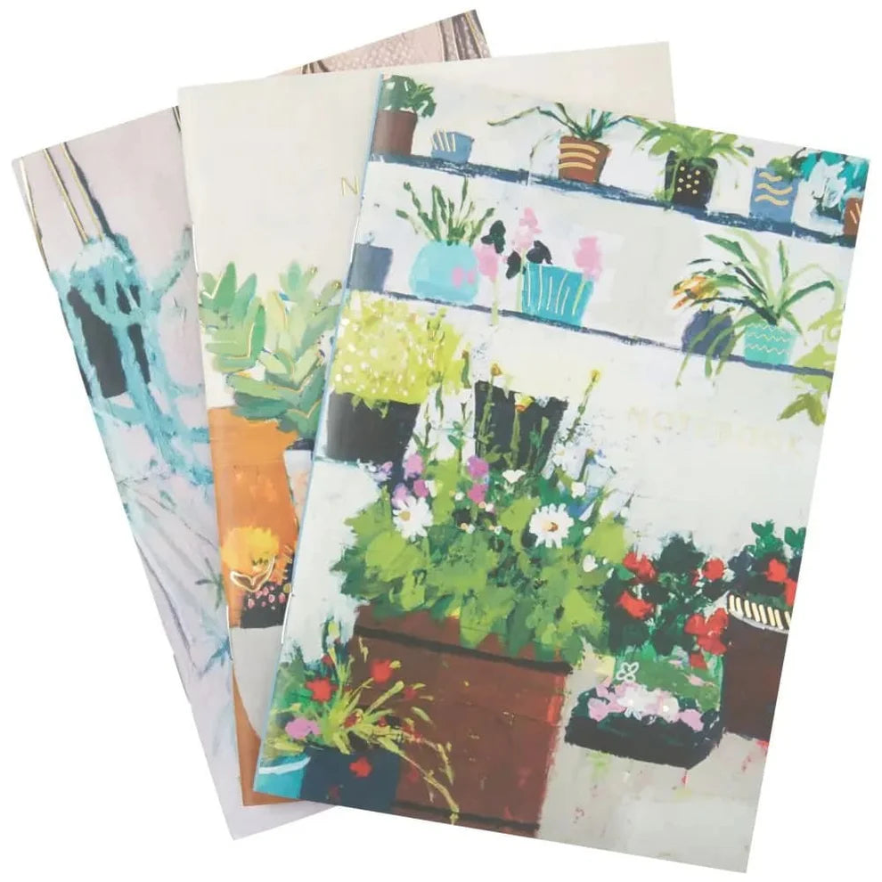 Set of three notebooks with garden-themed covers on a white background