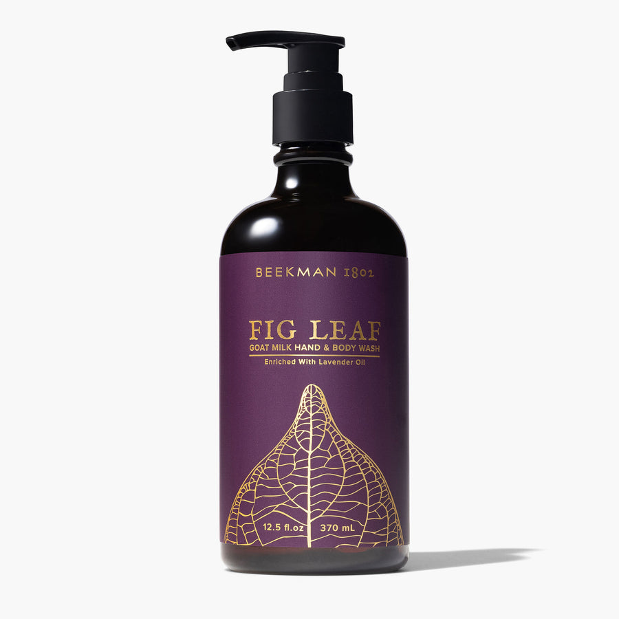 pump bottle of fig leaf hand and body wash wrapped with a deep plum paper printed with gold fig leaf design.