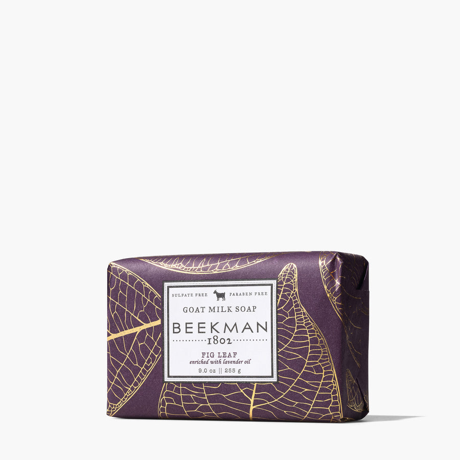 bar of soap wrapped in deep plum colored paper printed with gold fig leaf design.