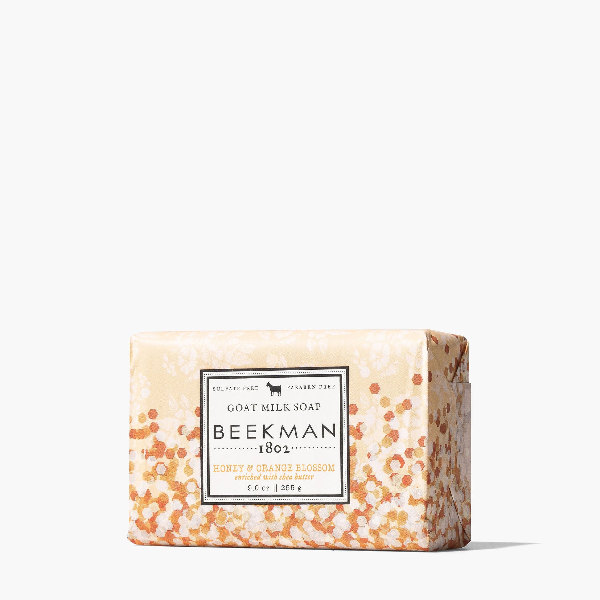 bar of honey and orange blossom soap wrapped in paper with an ombre pattern of dark to light orange dots.