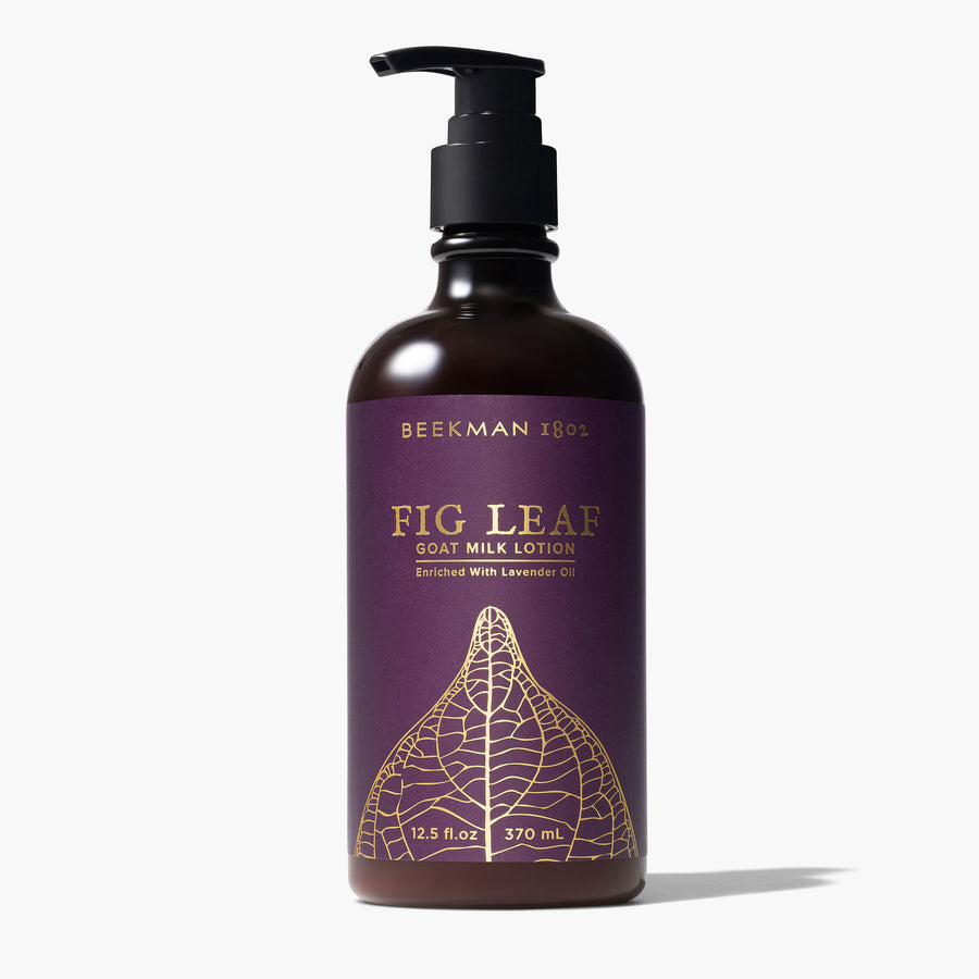 pump bottle of fig leaf lotion wrapped with a deep plum paper printed with gold fig leaf design.