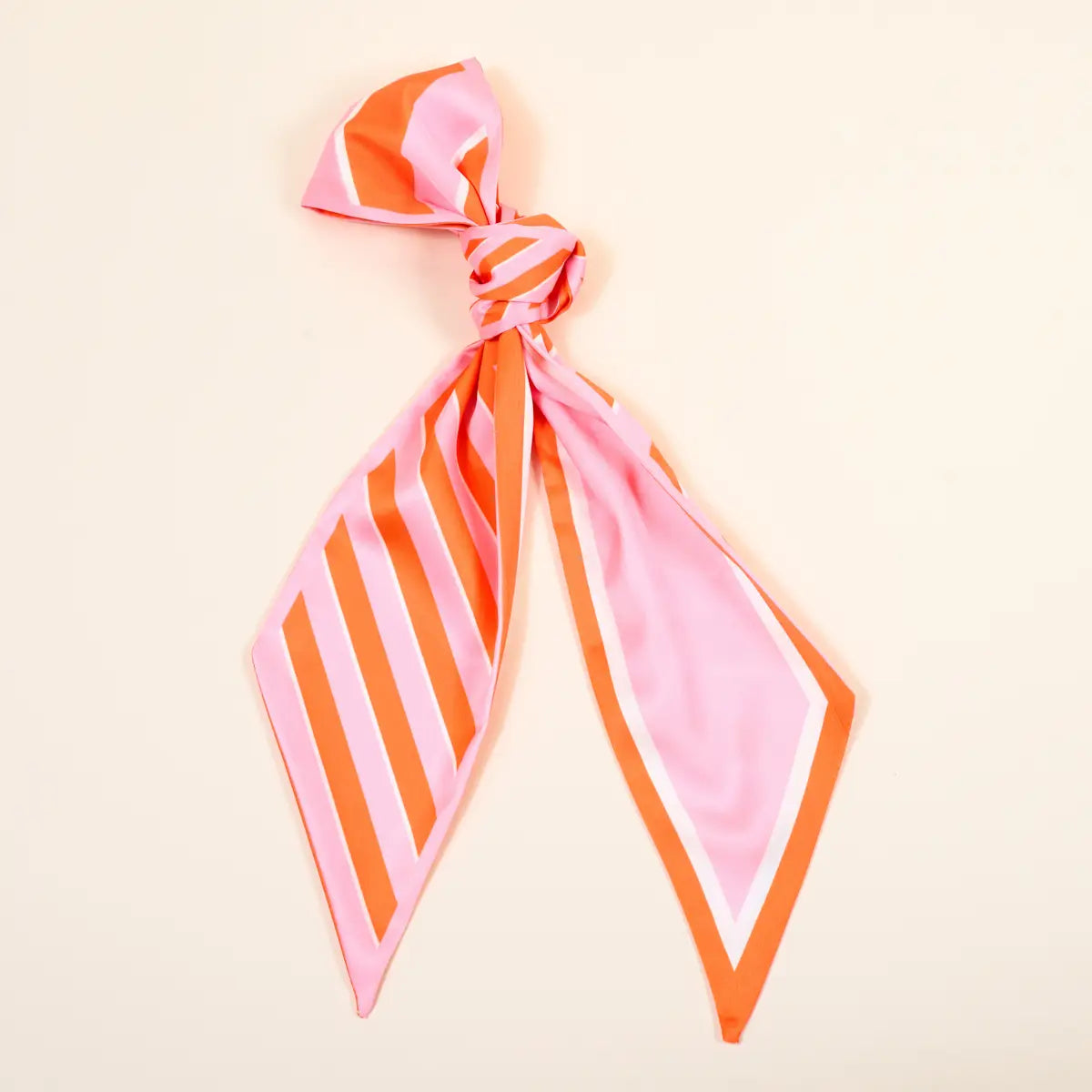 Pink and orange striped scarf tied into a knot on a beige background