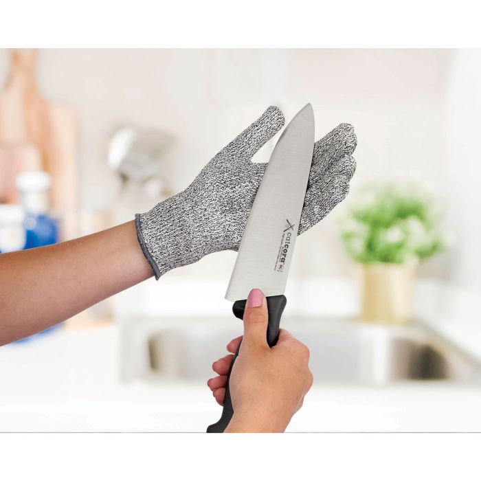 Person holding a knife with a cut-resistant glove in a kitchen setting