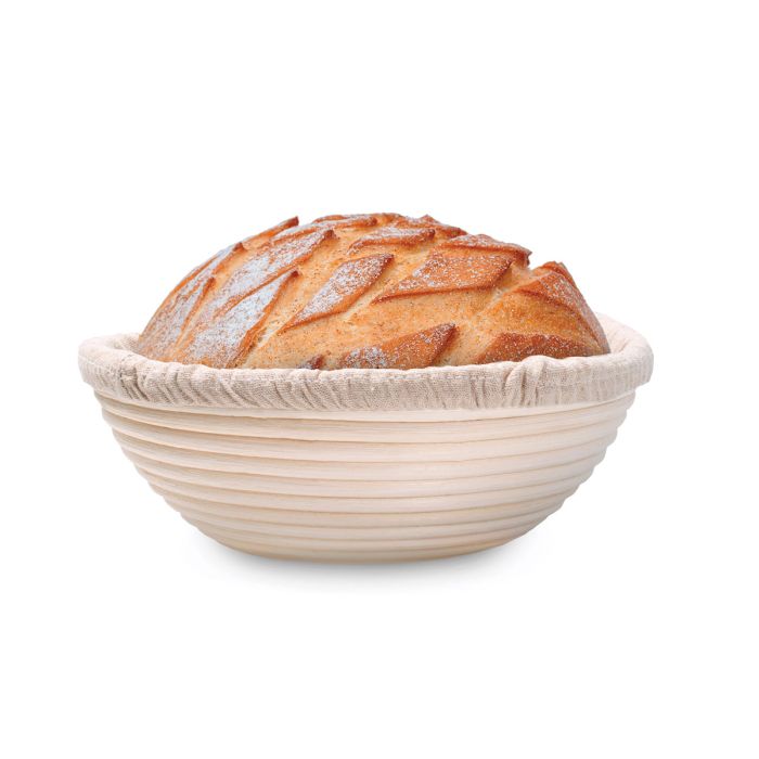 Loaf of bread in a round, proofing basket on a white background