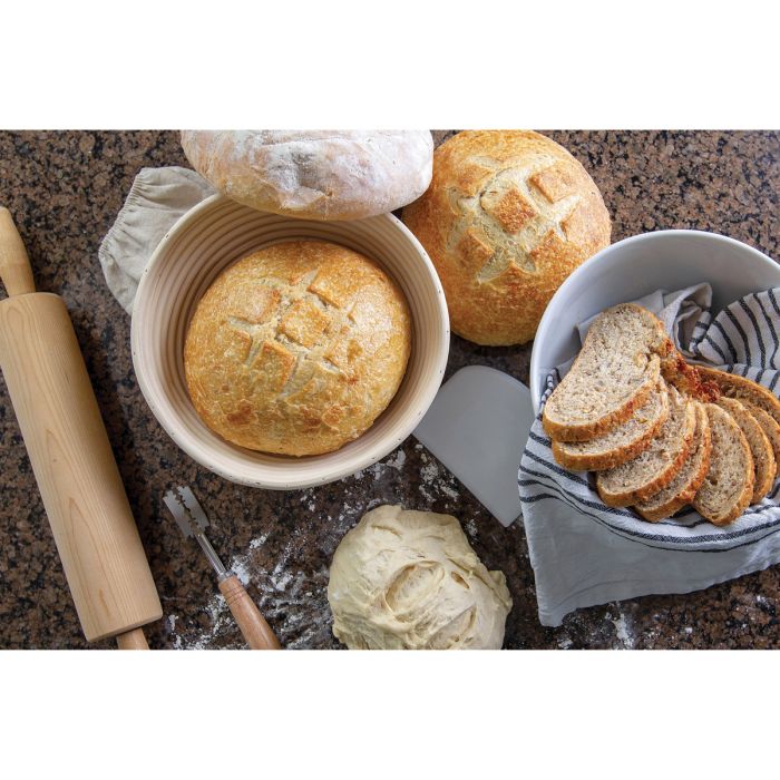 Baked bread in baskets with a rolling pin and knife on a countertop
