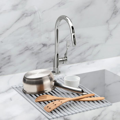 unrolled drying rack laying across a sink with a pan and utensils on it.