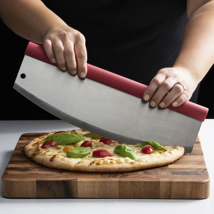 Person using a pizza cutter to slice a pizza topped with tomato and basil on a wooden board