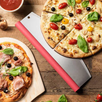 Two pizzas on a wooden table with a pizza cutter, surrounded by ingredients.