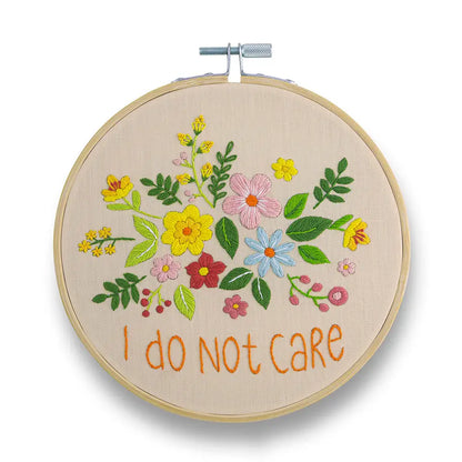 Embroidery hoop with floral design and 'I do not care' text on a white background