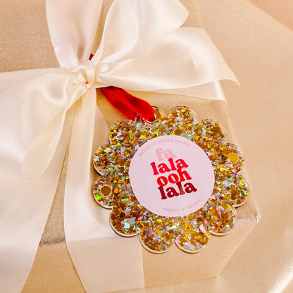 gold glitter Scalloped Acrylic Frame Ornament tied in an ivory bow of a wrapped gift