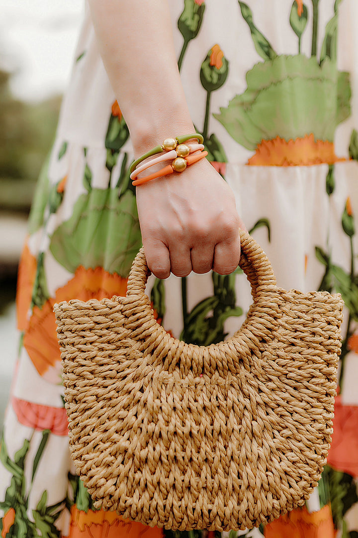 person carrying a straw purse and wearing 3 Bali 24K Gold Plated Bead Silicone Bracelet on her arm.