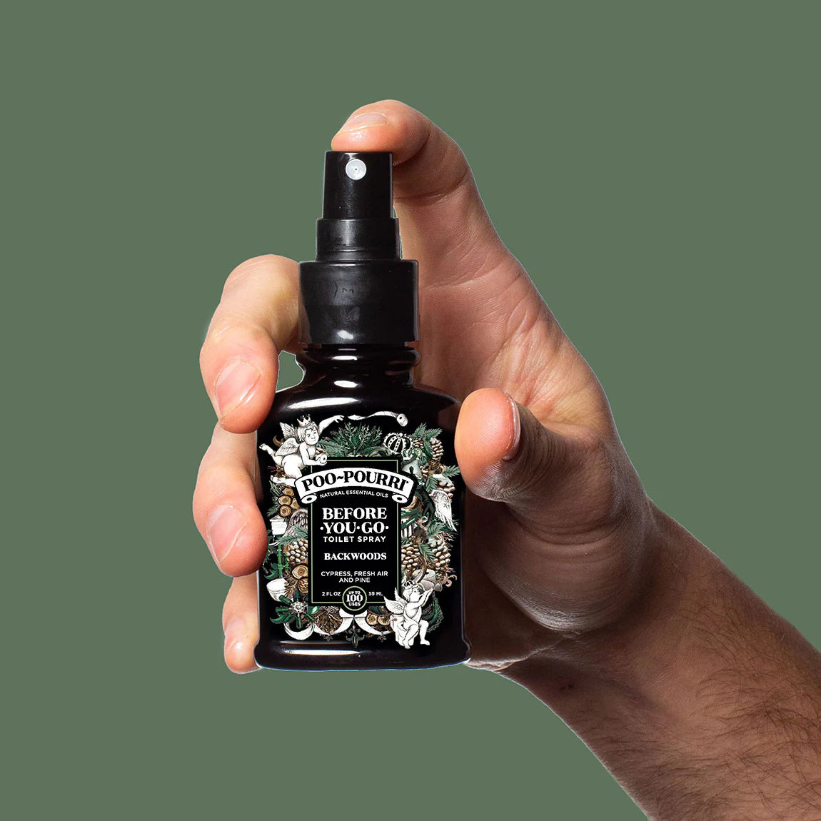 hand holding bottle of backwoods toilet spray with finger on the pump.