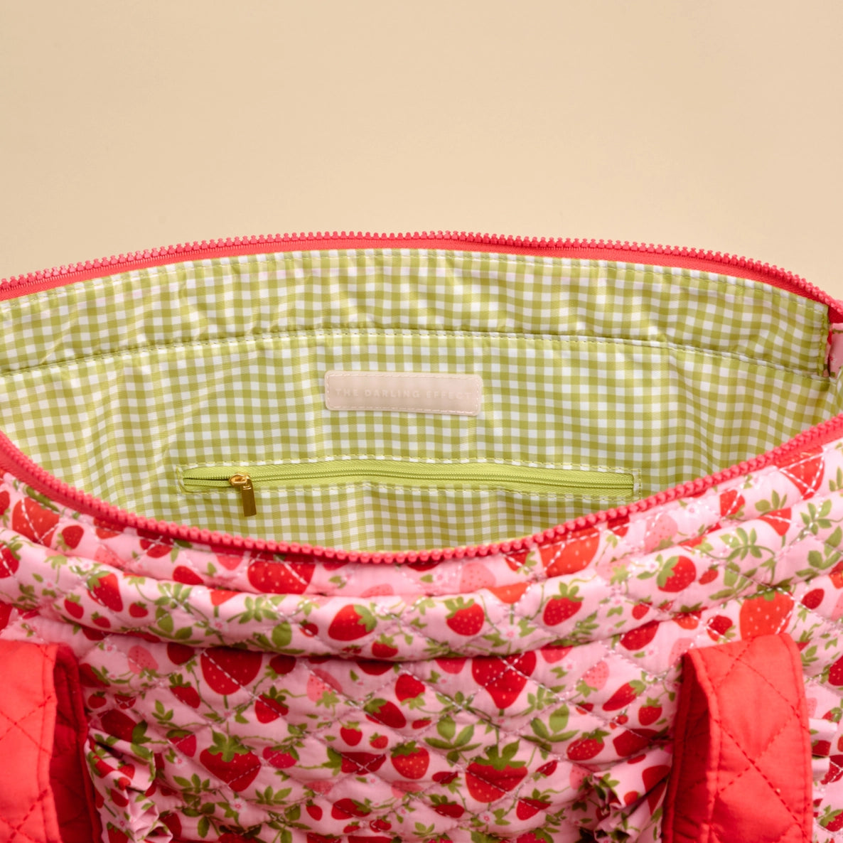 Close-up of a fabric bag with strawberry pattern and green checkered interior.