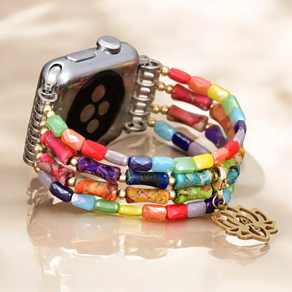 Colorful beaded watch strap with gold lotus charm on a neutral background