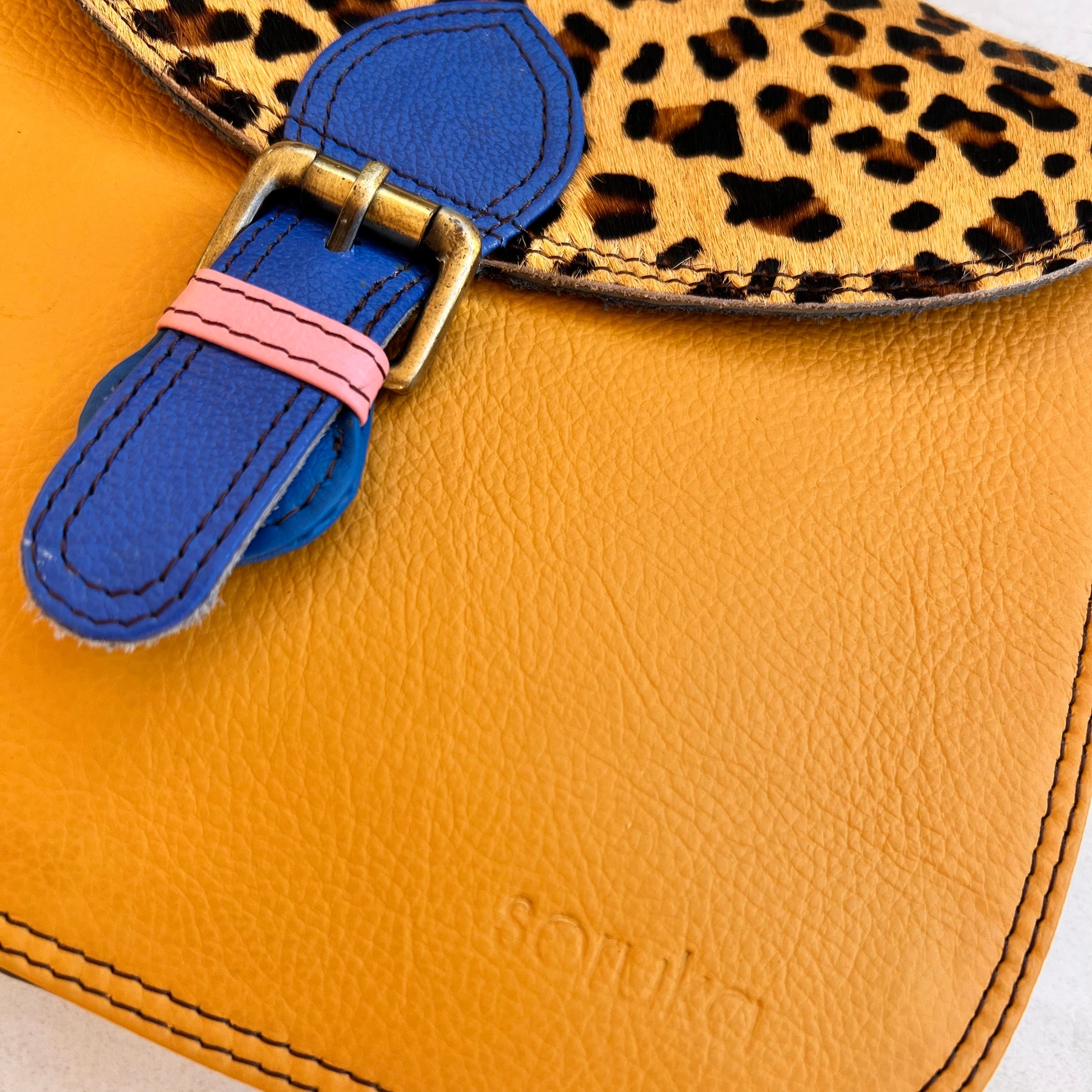 close-up of front blue buckle of honey quinn bag.