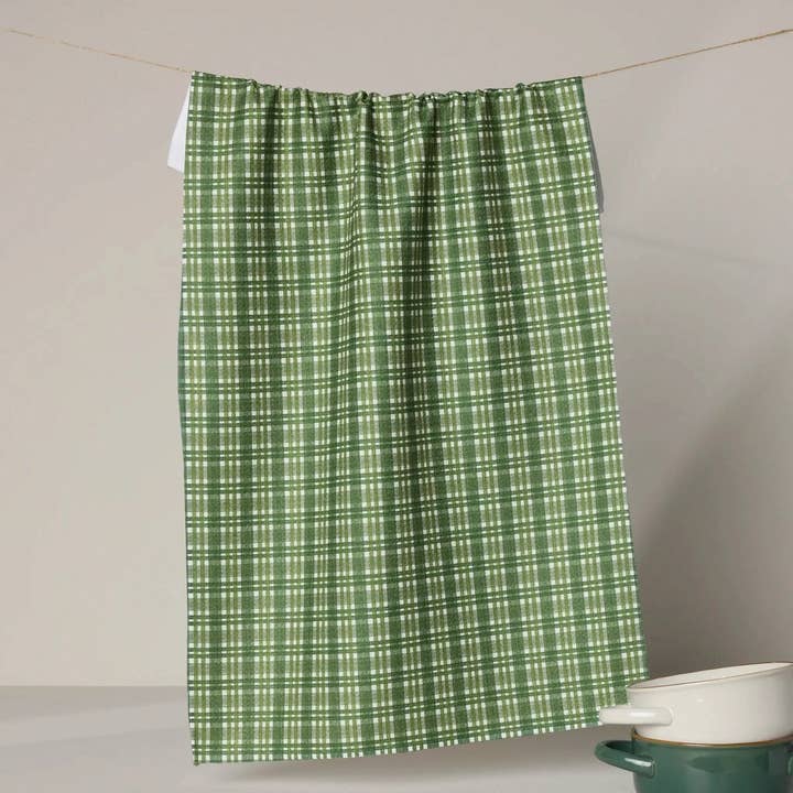shay plaid tea towel partially hanging on a clothesline shown on a grey background