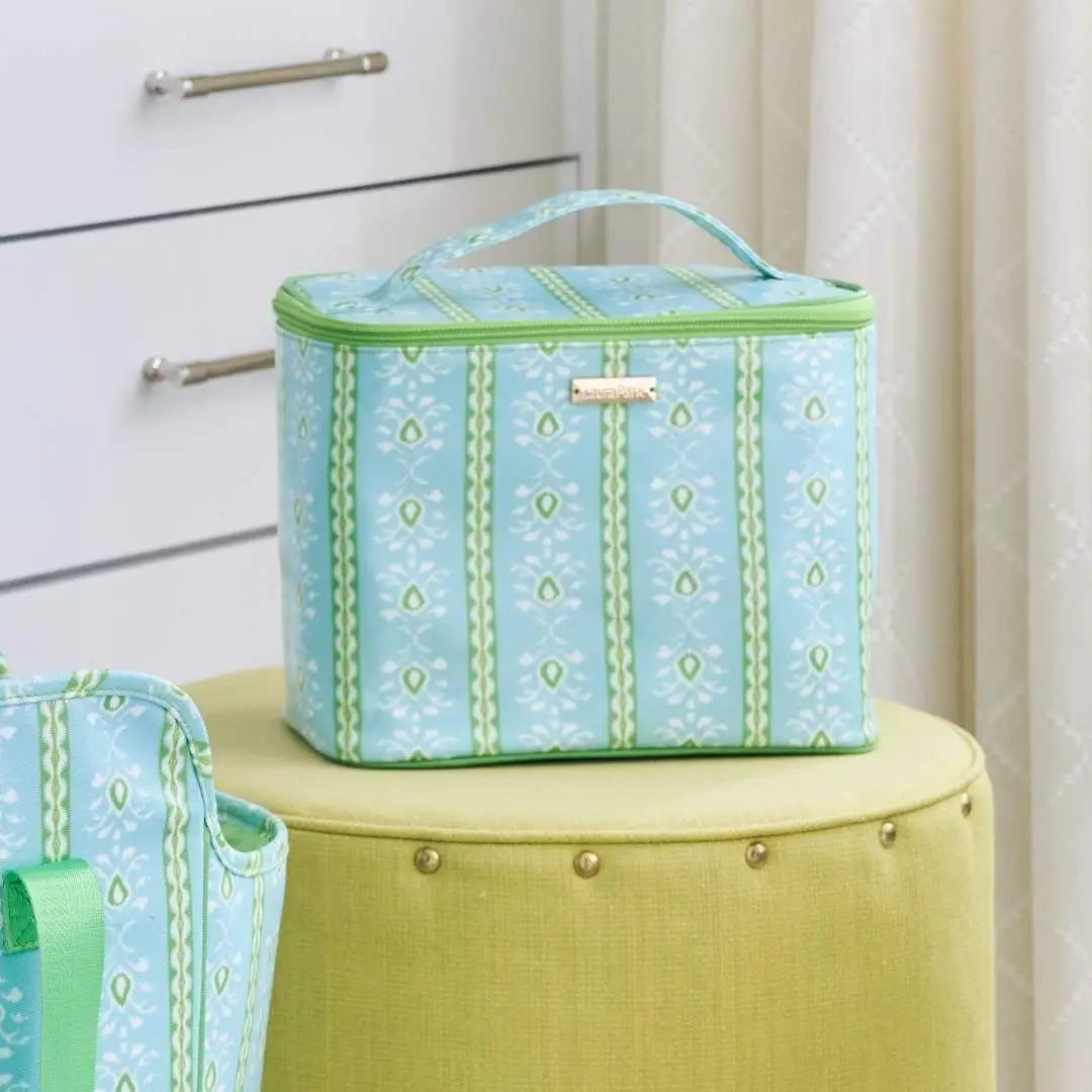 rosemary strip train case set on a decorative stool with a chest of drawers in the background