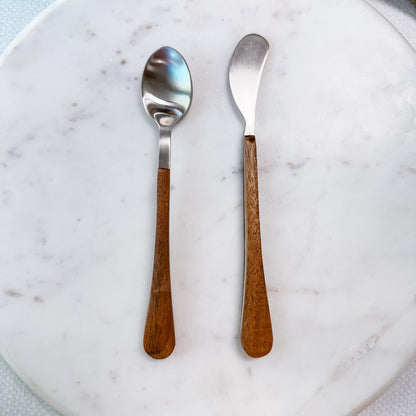 small spoon and spreader with wooden handles arranged on a marble surface.
