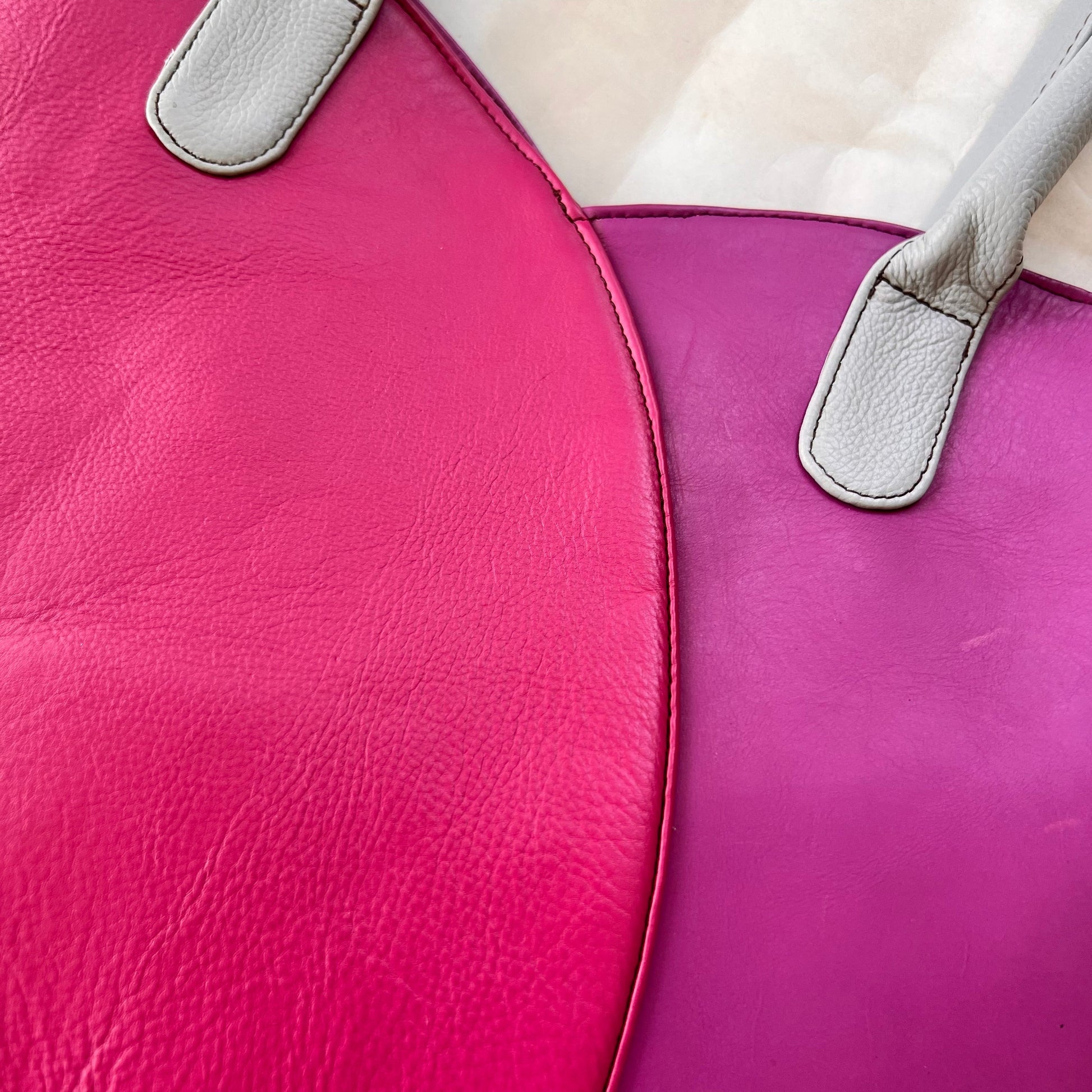close-up of valeria tote that is half pink and half light plum with grey handles.