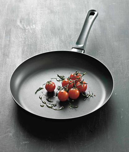 Frying pan with cherry tomatoes in it on a gray background