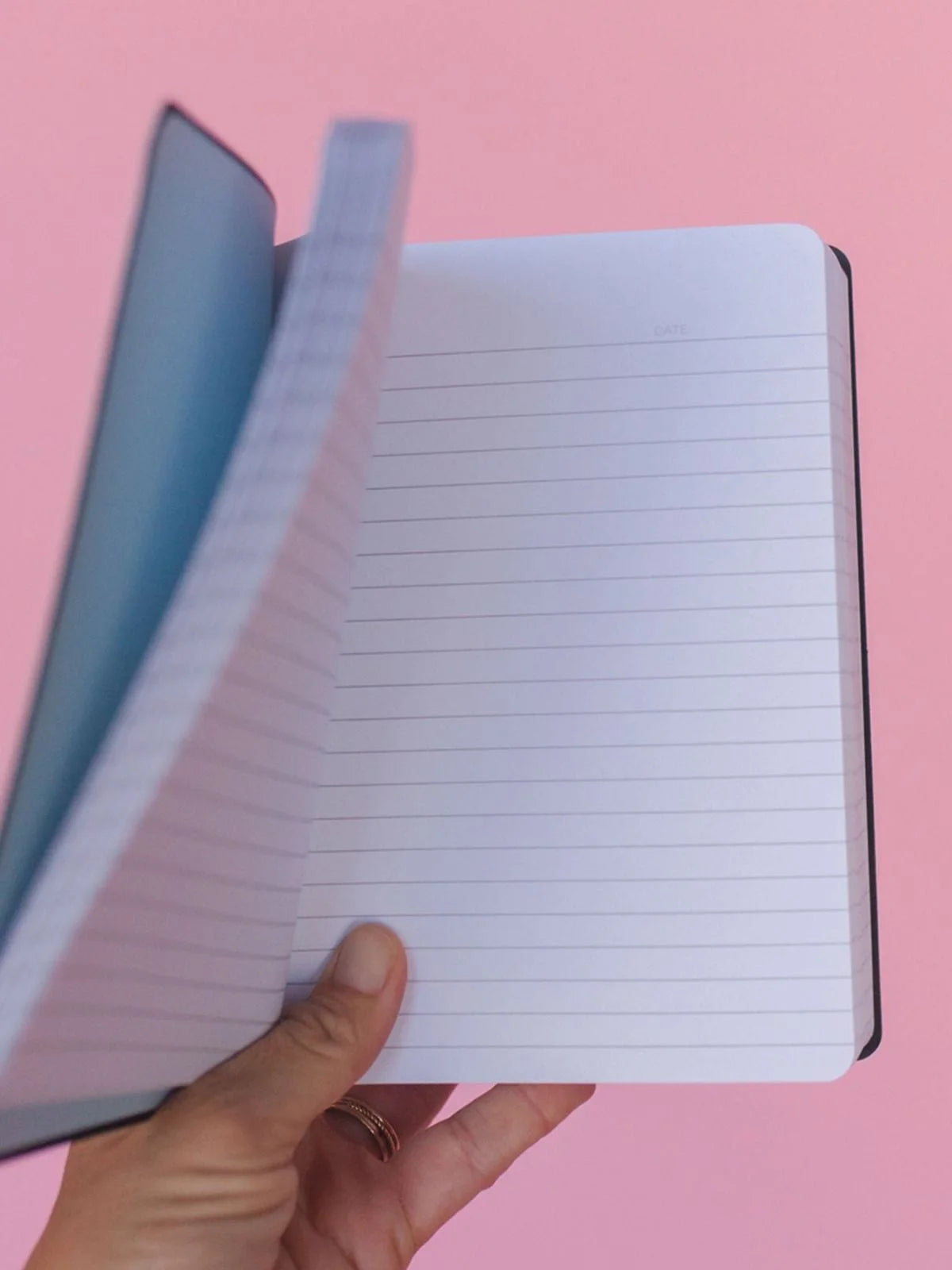 a person holding a notebook open to show lined pages