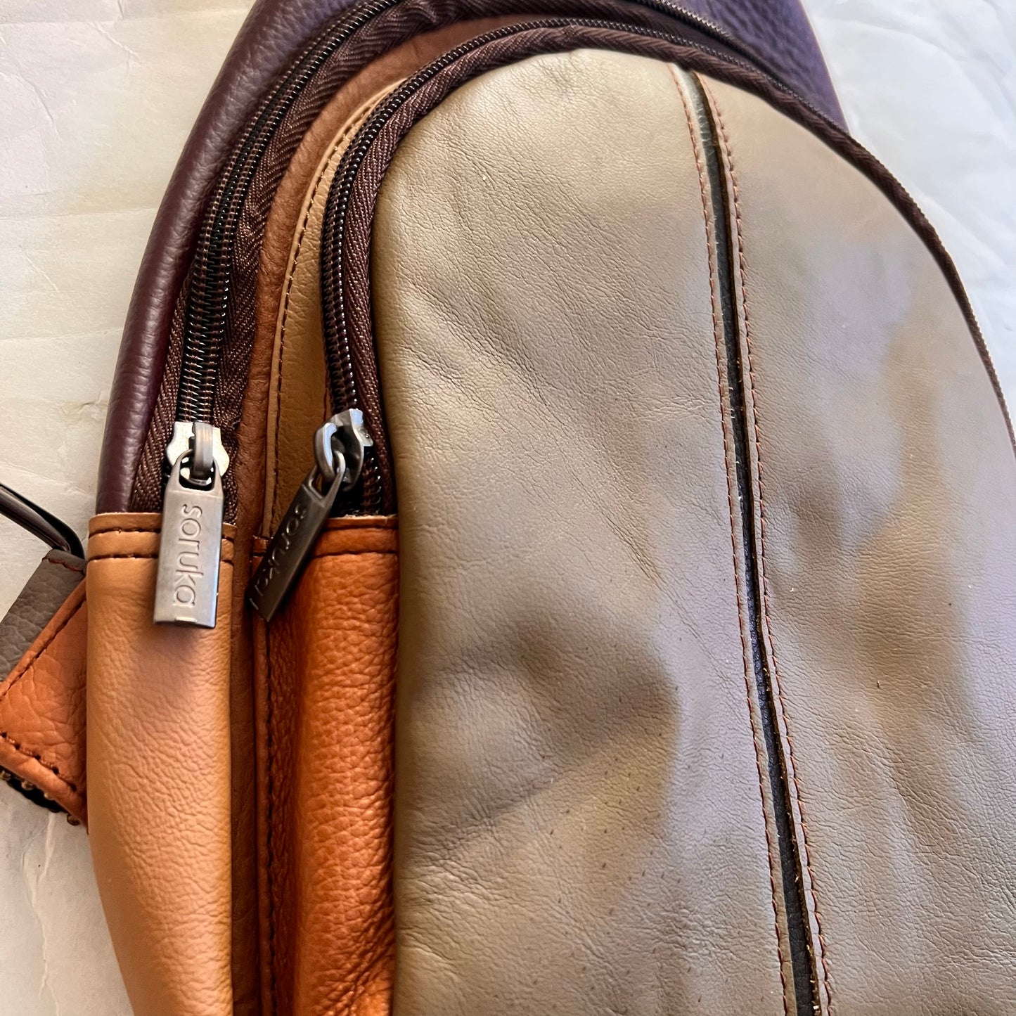 side view of taupe Gregg sling bag.
