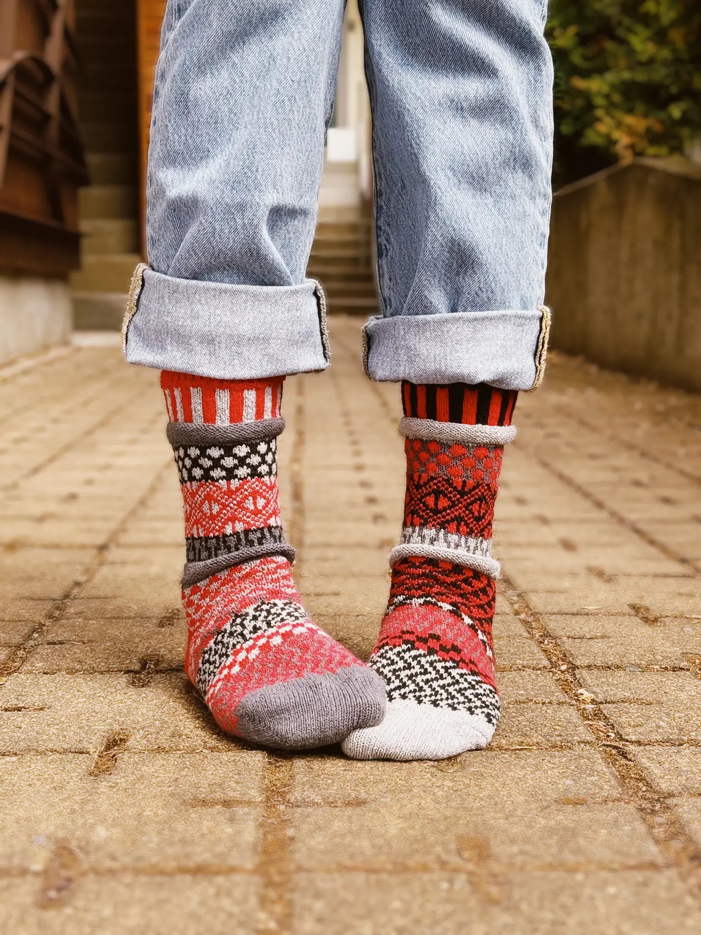 close-up of person from the knee standing on a brick patio wearing Mercury Crew Socks with their jeans rolled up a few times.