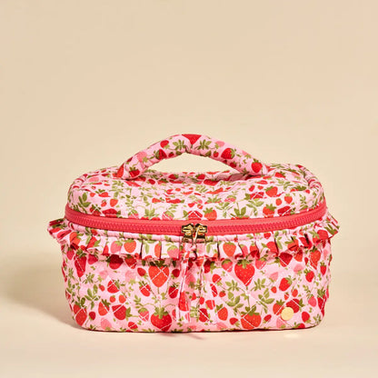 pink cosmetic bag printed with strawberry design shown on a beige background