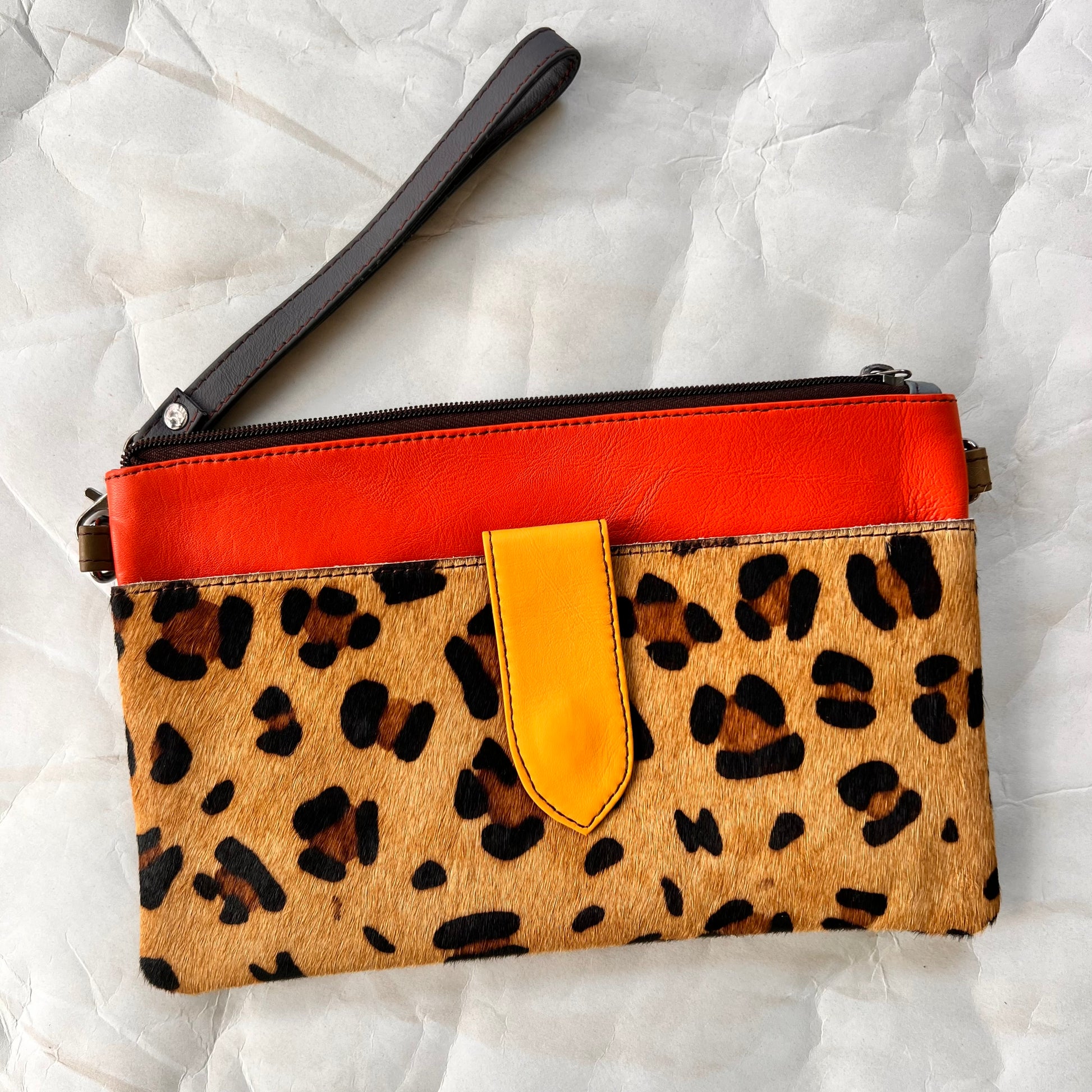 orange rectangular bag with cheetah print pocket, grey wristlet strap.