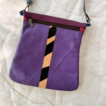 purple greta bag with animal print stripe down the center and zipper at the top.