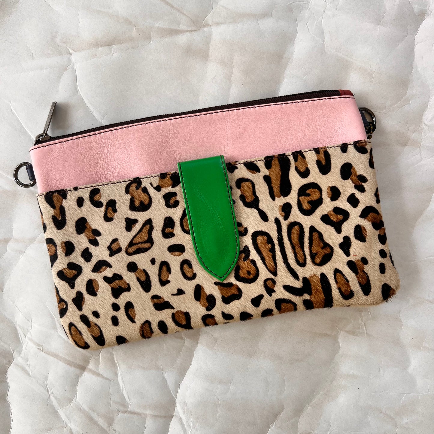 pink rectangular bag with cheetah print hair-on-hide pocket, and green tab.