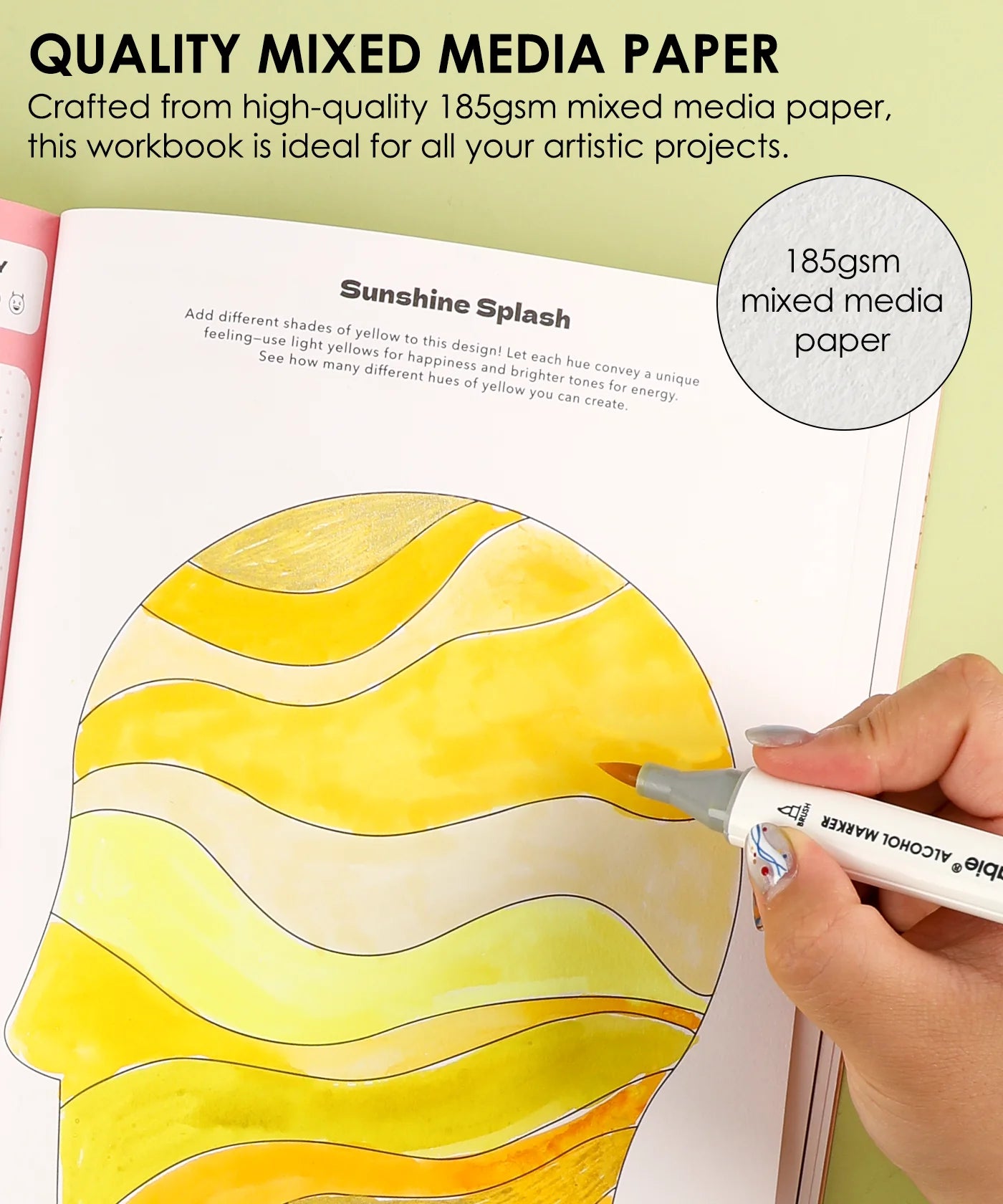 Workbook with yellow and orange design on mixed media paper, featuring a hand holding a marker.