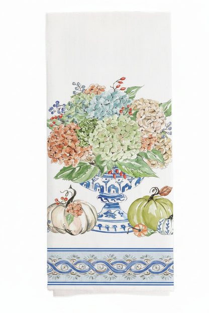 tea towel with image of a hydrangea bouquet in a blue and white urn with pumpkins and a flourished boarder along the bottom