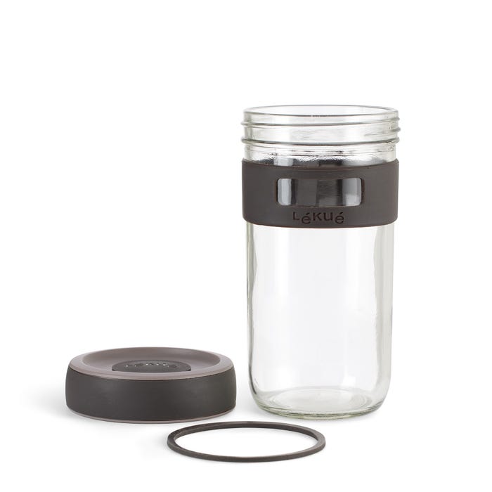 empty glass jar with silicone band around it and lid and ring set next to it on a white background.