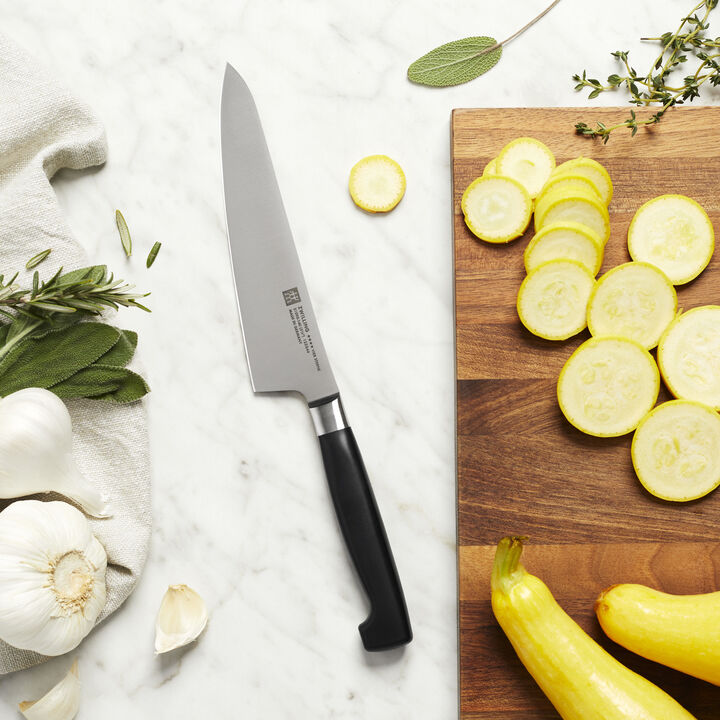 Four Star 5.5 Inch Fine Edge Prep Knife laying on a counter with a cutting board, sliced veggies, and fresh herbs.