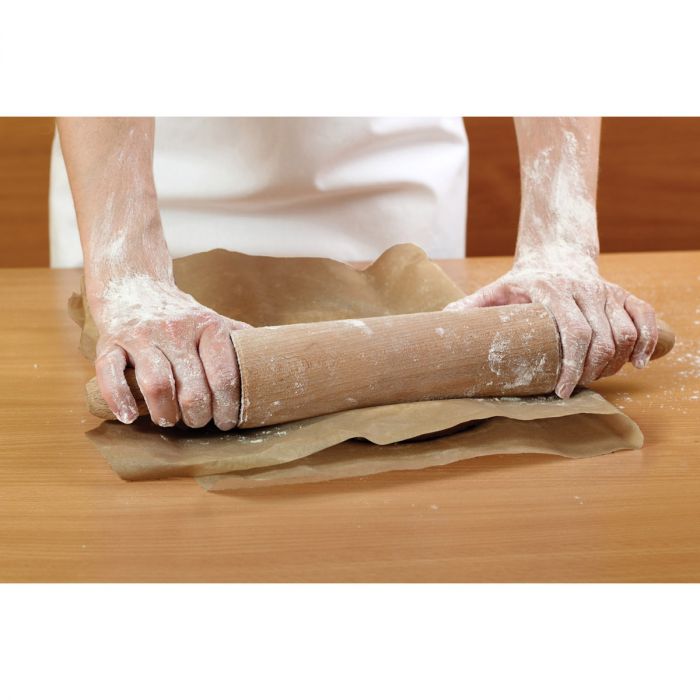 hands rolling dough between sheets of parchment paper