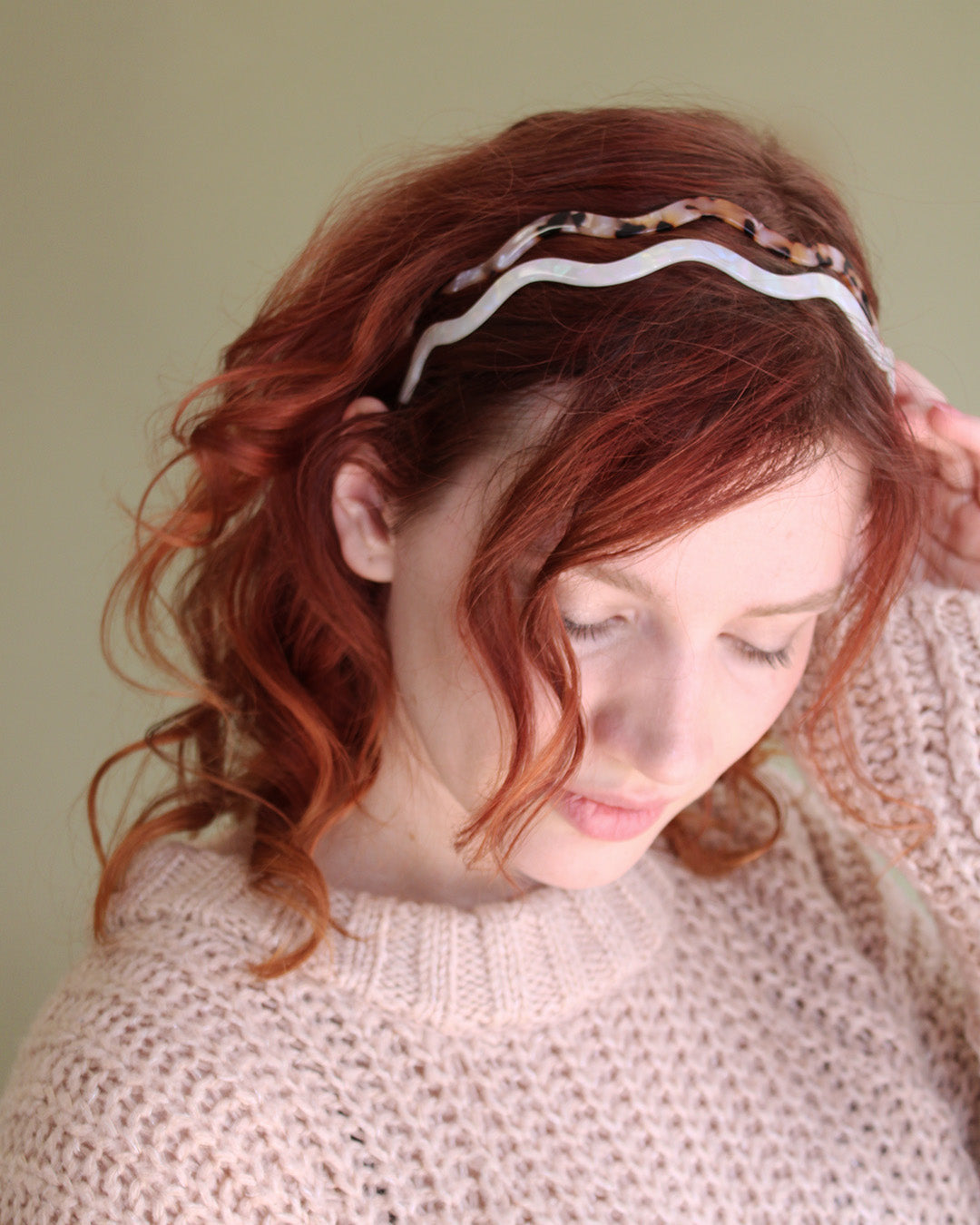 person with red wavy hair wearing 2 verdant glade headbands.