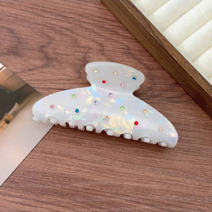 White Claw Clip with Rainbow Rhinestones on a wood desk