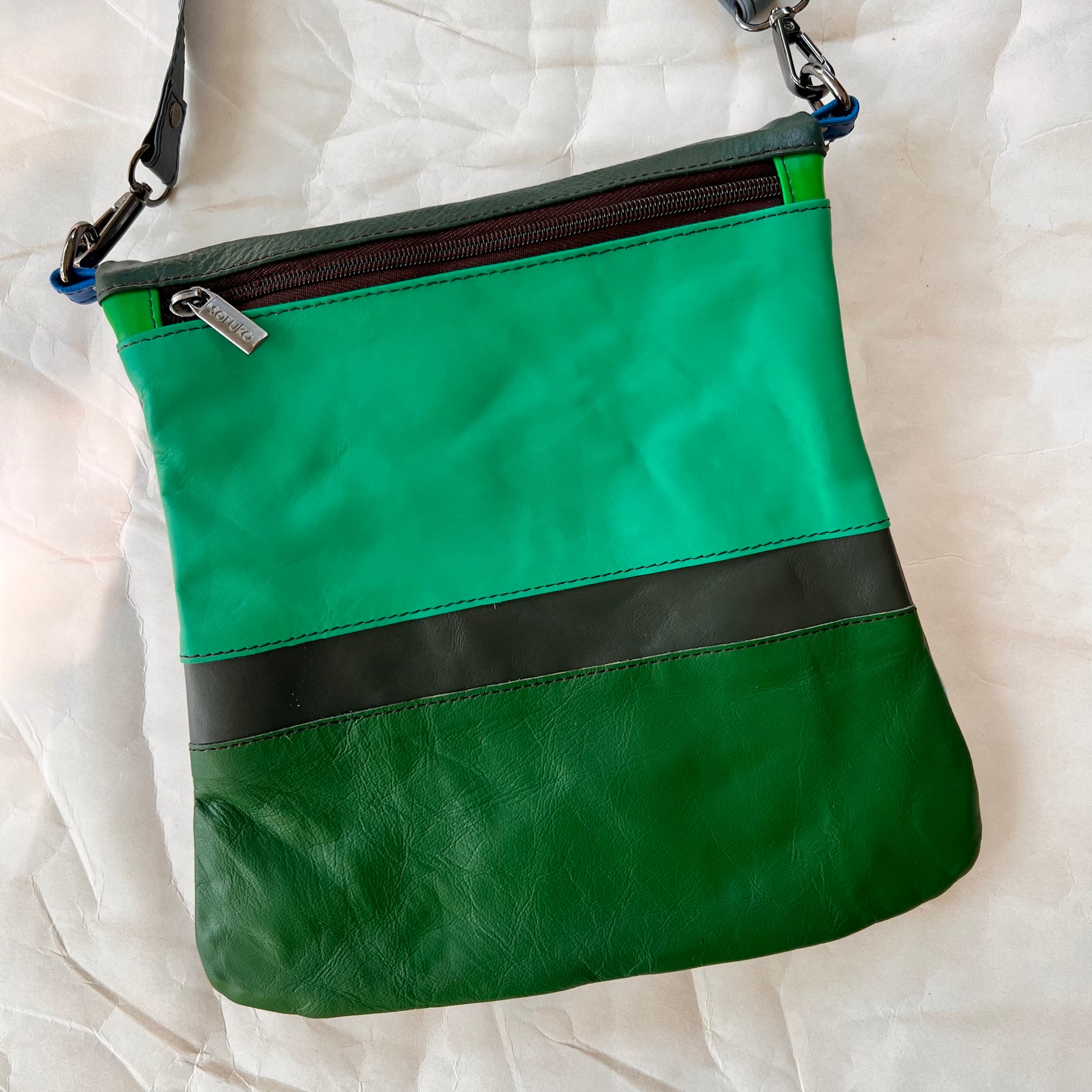 greens and grey striped greta bag with zipper across the top.