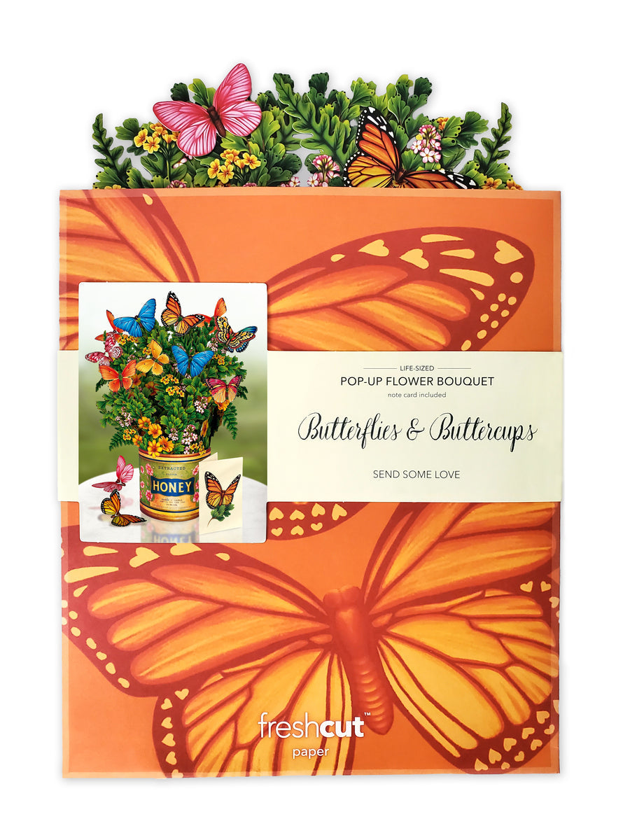 Butterflies & Buttercups bouquet flat and in its mailing envelope that is orange with butterflies printed on it.