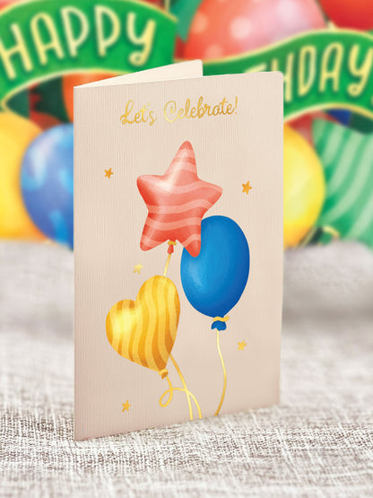 classic balloon inspired pop up card with gold text saying "Let's celebrate!"